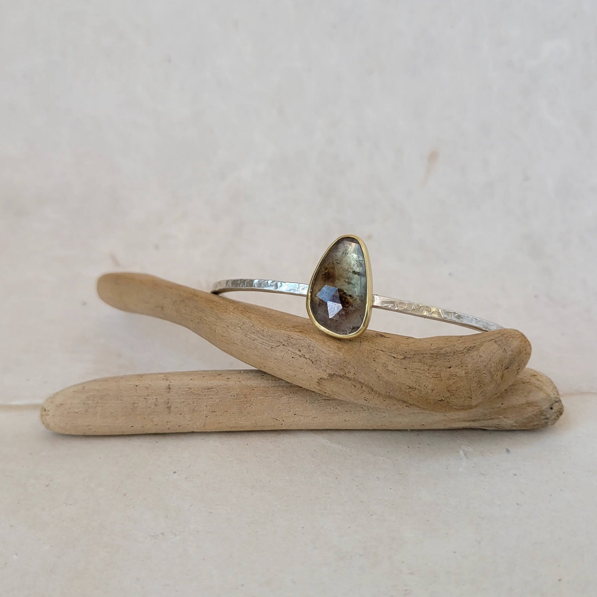 Rose cut sapphire bezel set in yellow gold on a hammered sterling silver cuff.