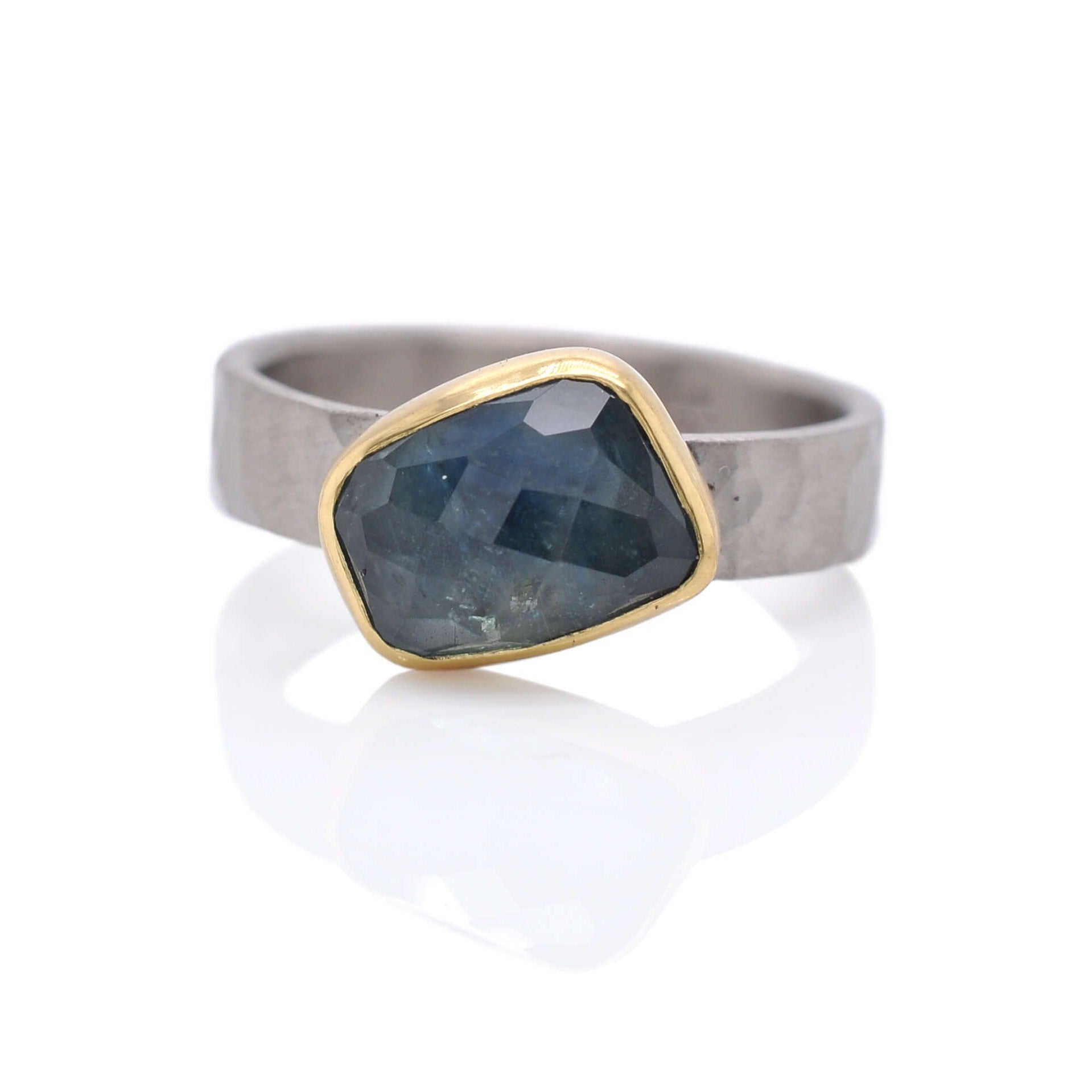 Blue sapphire ring bezel set with yellow gold on a hammered band of palladium. Handmade by EC Design Jewelry in Minneapolis, MN.