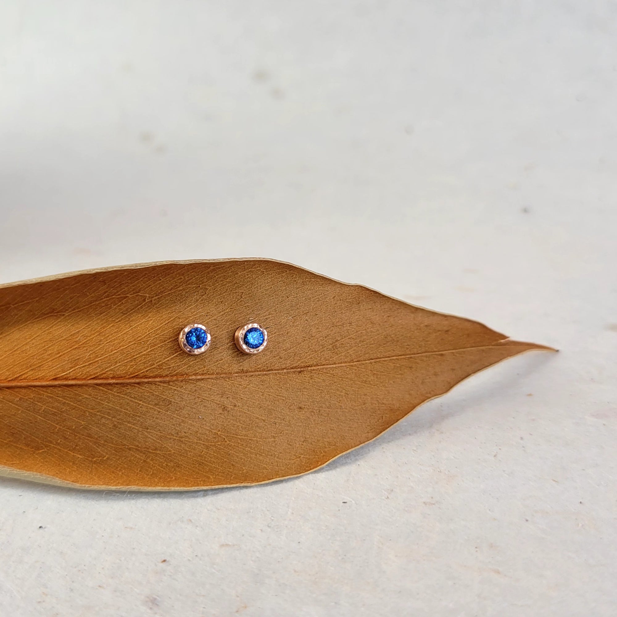 Round Brilliant Blue Sapphire Stud Earrings in Hammered Rose Gold