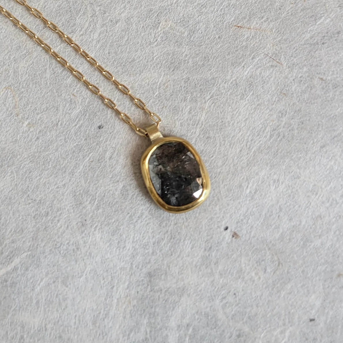 Diamond pendant in a solid gold setting on a gold chain.