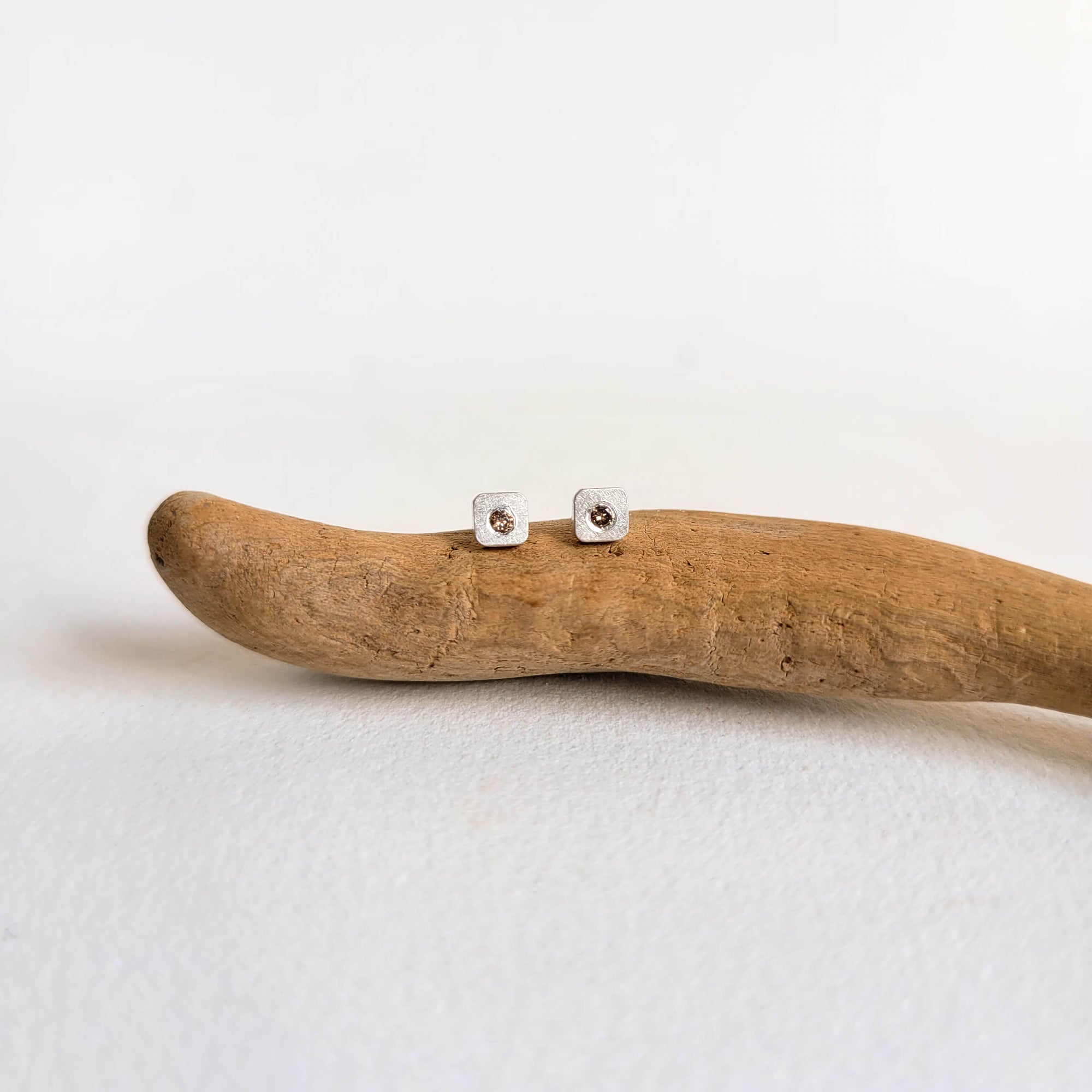 Hammered sterling silver studs with center-set champagne diamonds. Handmade by EC Design Jewelry in Minneapolis, MN.