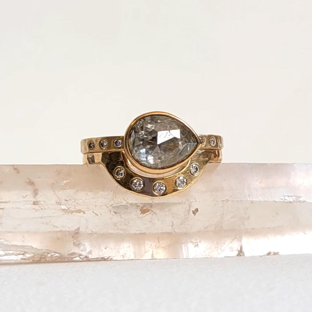 Gold ring with a large central gemstone on a light stone surface