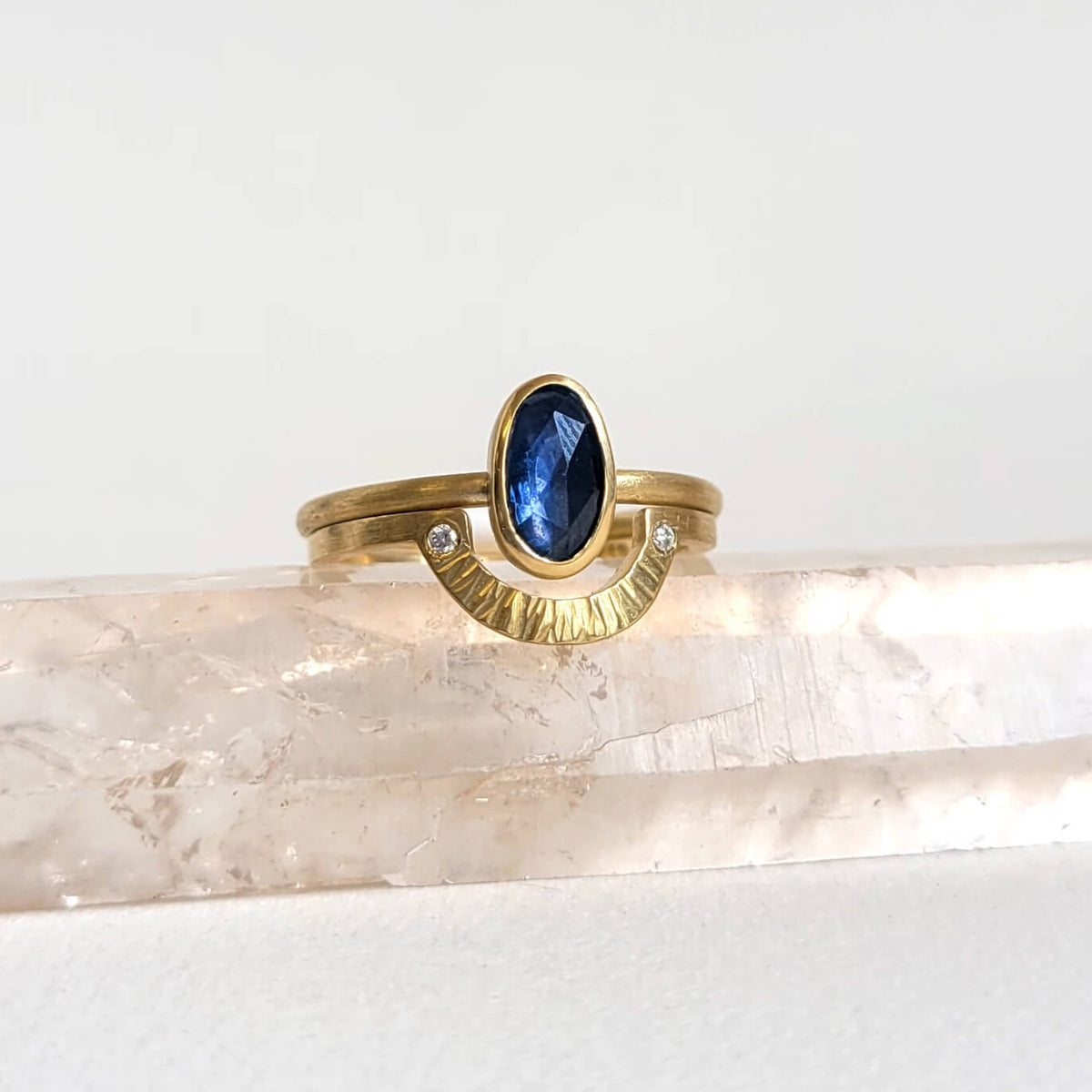 Gold ring with a blue gemstone on a clear crystal point against a white background