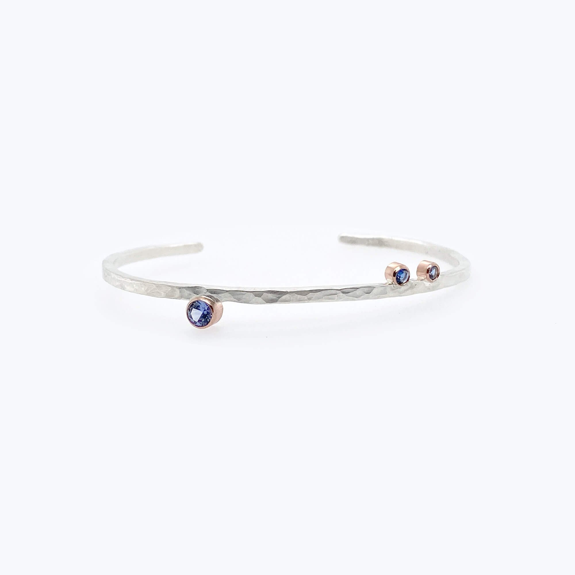 Sterling silver cuff with rose gold bezel set blue sapphires.