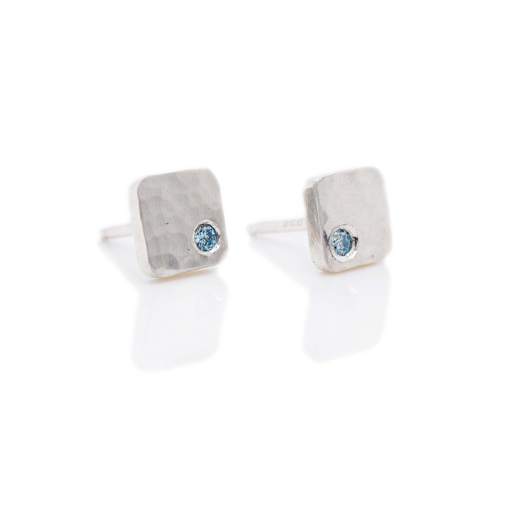Hammered sterling silver square studs with flush set aqua diamonds. Handmade by EC Design Jewelry in Minneapolis, MN.