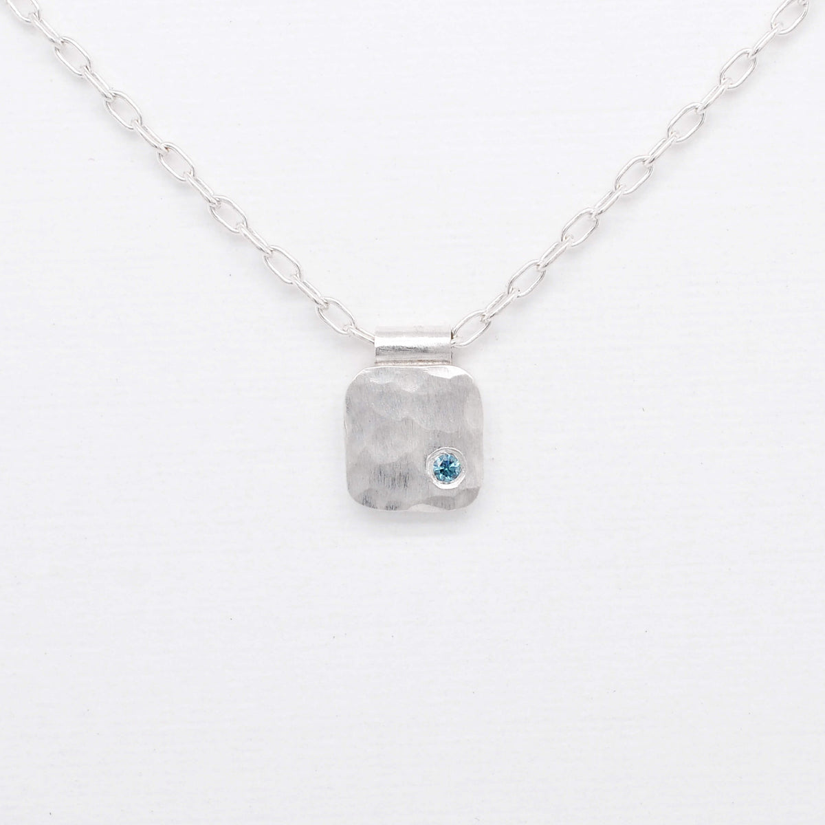 Hammered silver cell pendant with teal blue diamond. Handmade by EC Design Jewelry in Minneapolis, MN.