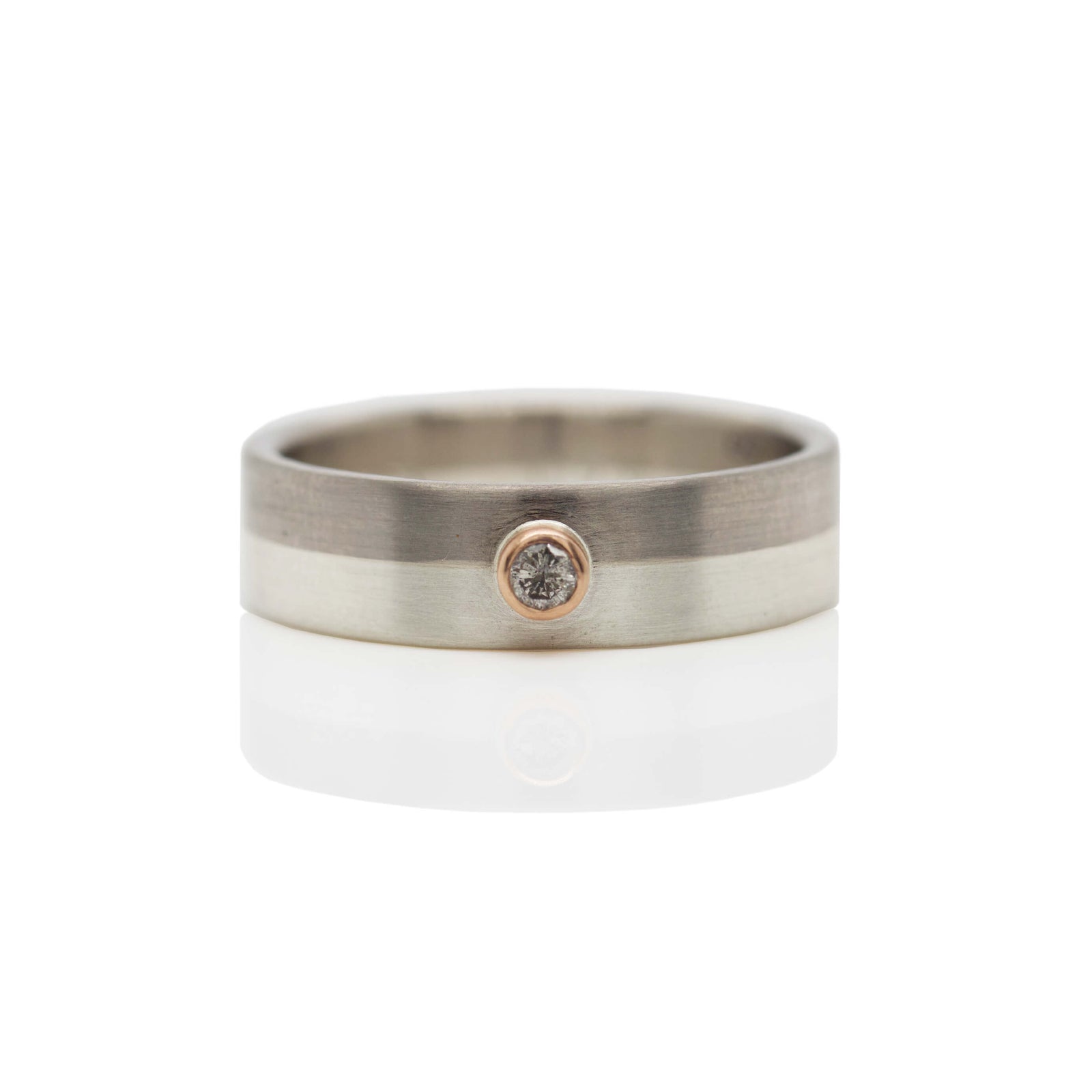 Monotone wedding band with rose gold bezel set diamond accent. Handmade by EC Design Jewelry in Minneapolis, MN.