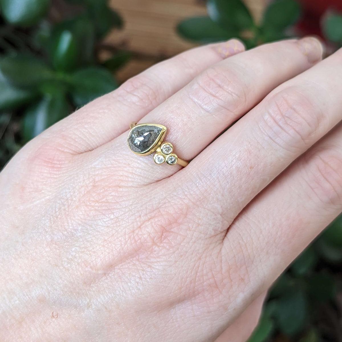 Tilted teardrop salt and pepper cluster ring in yellow gold.