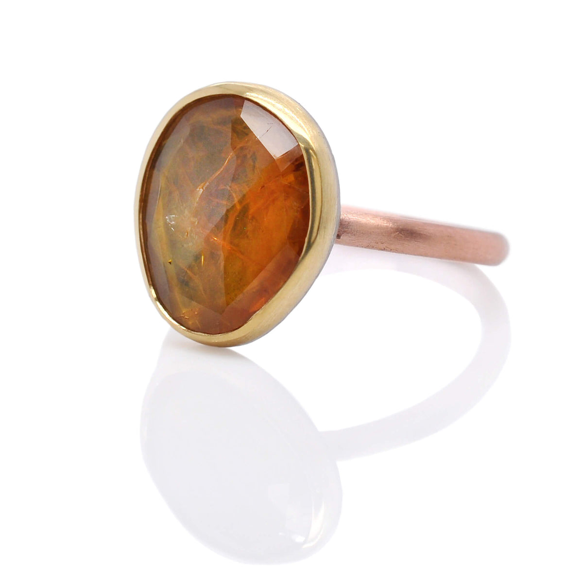 Organic orange sapphire bezel set in yellow gold on a satin finished rose gold band. Handmade by EC Design Jewelry in Minneapolis, MN.