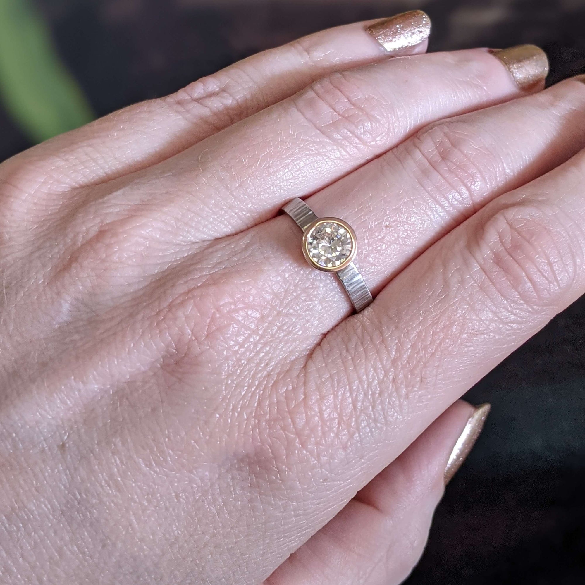 Moissanite engagement ring in red gold on a hammered palladium band. Handmade by EC Design Jewelry in Minneapolis, MN using recycled metal and conflict-free stone.