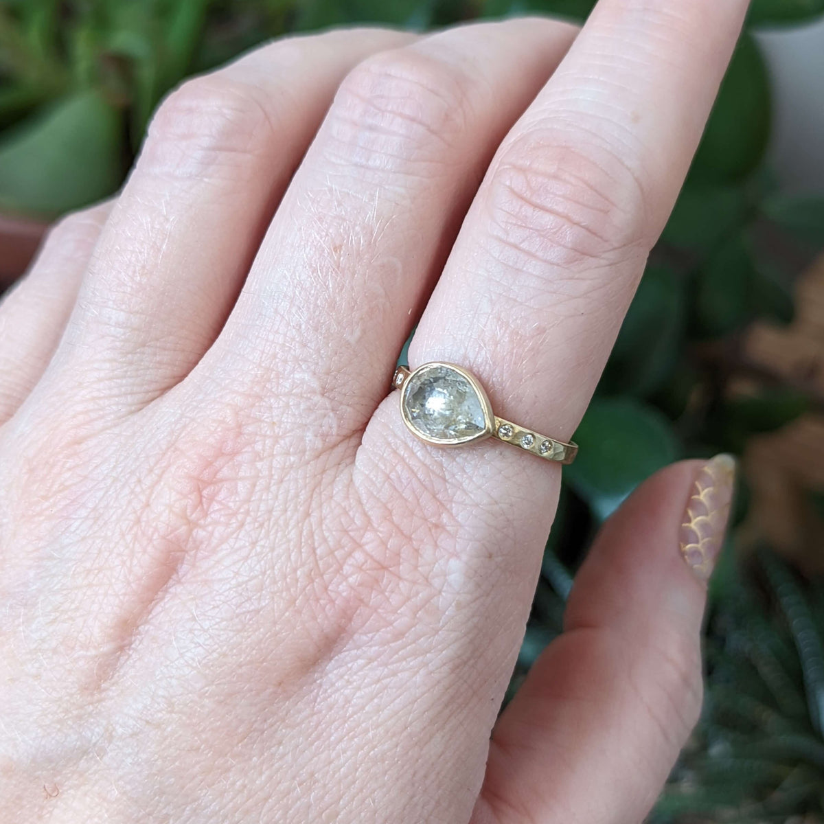 Lemony yellow teardrop shaped ice diamond engagement ring on a hand hammered diamond band of yellow gold.