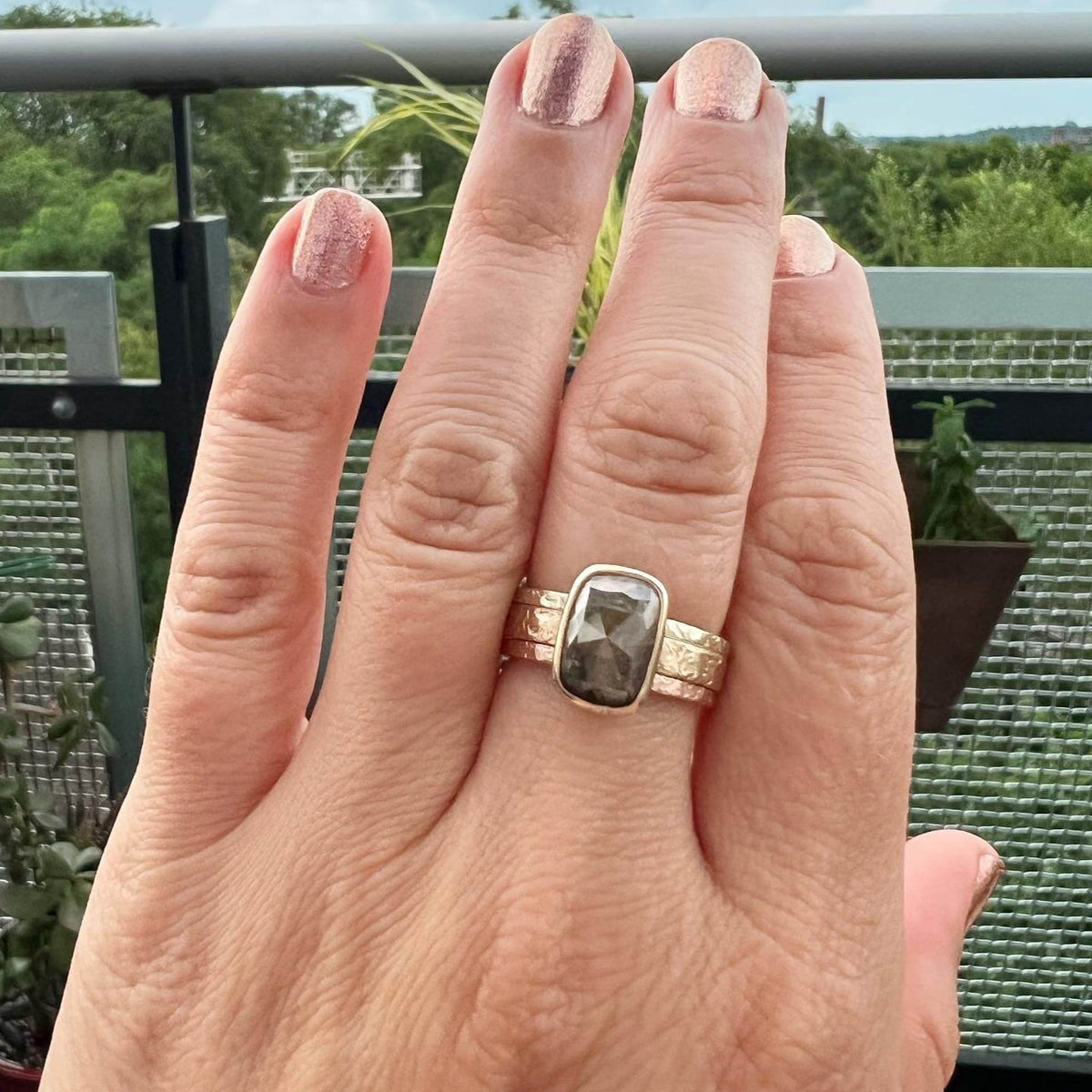 Champagne diamond engagement ring in yellow gold with rose gold and green gold stacking bands. Each ring is handmade and has a silk hammered texture.