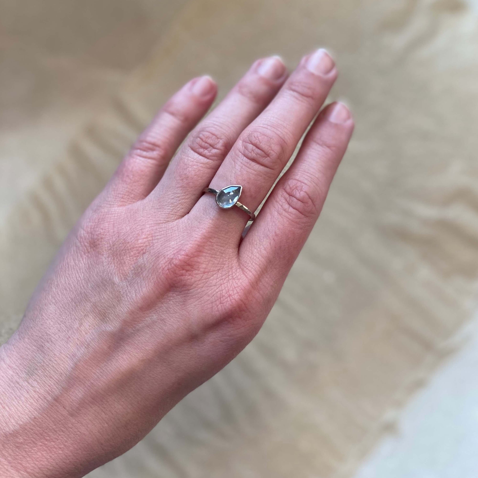 Tilted gray-blue pear shaped sapphire and palladium white gold engagement ring. Handmade with recycled metal and conflict-free stone. EC Design Jewelry in Minneapolis, MN.