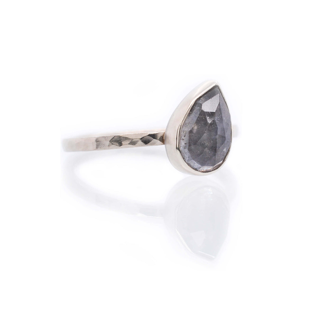 Blue gray tilted pear shaped sapphire on a hammered band of palladium white gold. Handmade with recycled metal and conflict-free stone. EC Design Jewelry in Minneapolis, MN.