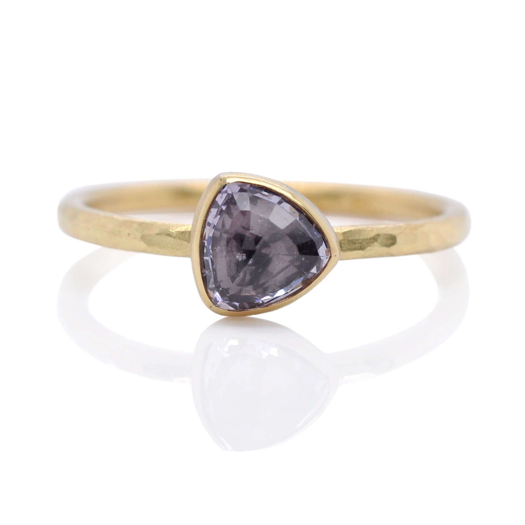 Purple trillion cut sapphire solitaire in hammered yellow gold.