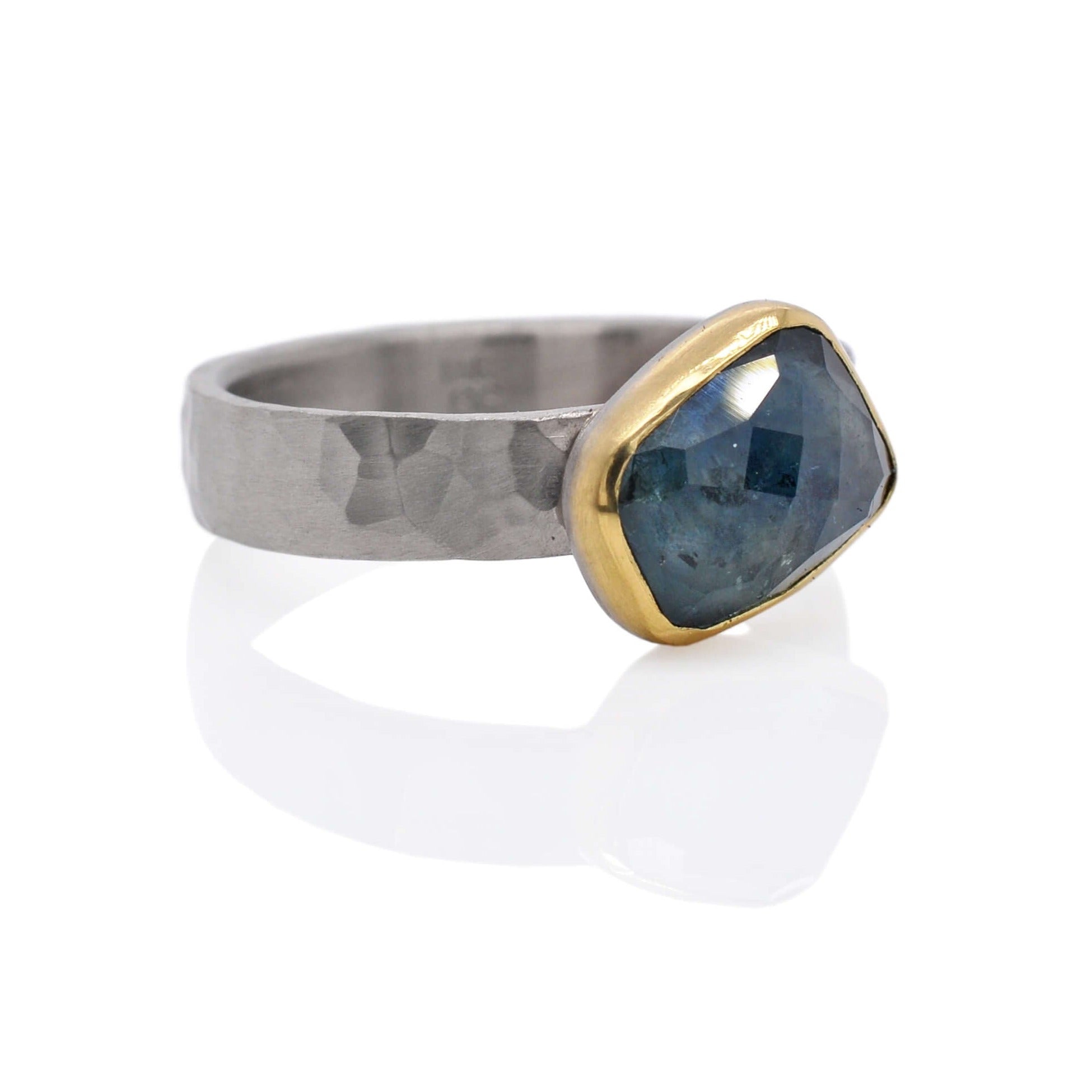 Blue sapphire ring bezel set with yellow gold on a hammered band of palladium. Handmade by EC Design Jewelry in Minneapolis, MN.
