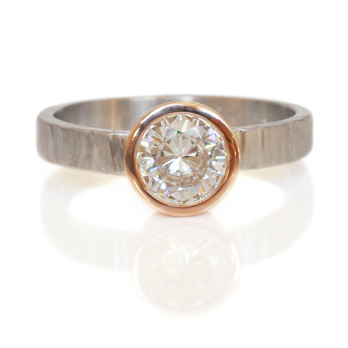 Moissanite engagement ring in red gold on a hammered palladium band. Handmade by EC Design Jewelry in Minneapolis, MN using recycled metal and conflict-free stone.